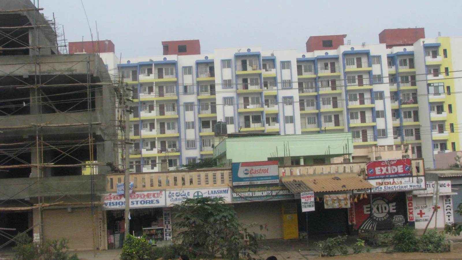 A white residential apartment building in Bengaluru with balconies on every floor, under a clear blue sky