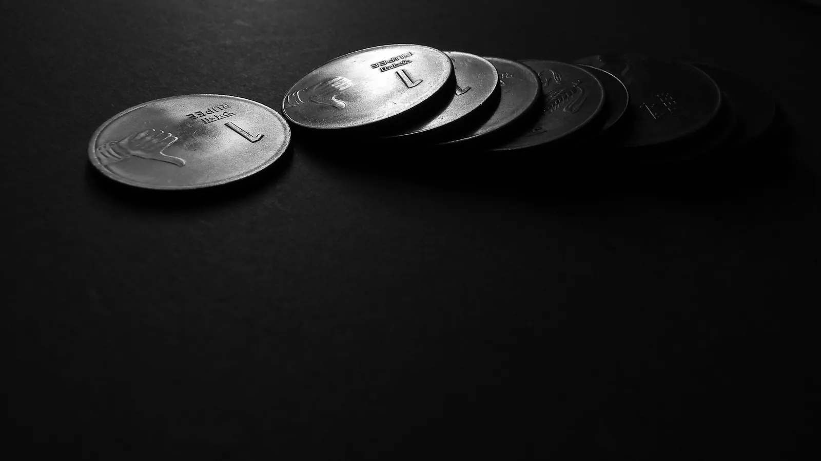 A row of coins catching the light on a dark surface