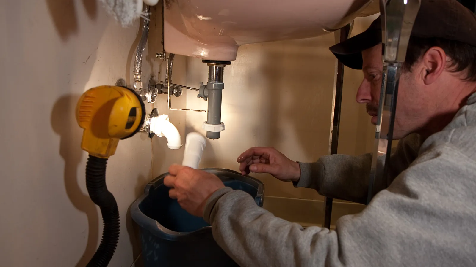 A technician repairing the plumbing under a kitchen sink