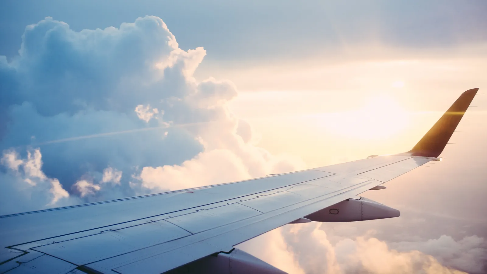 The wing of an aircraft above a sunlit bank of clouds