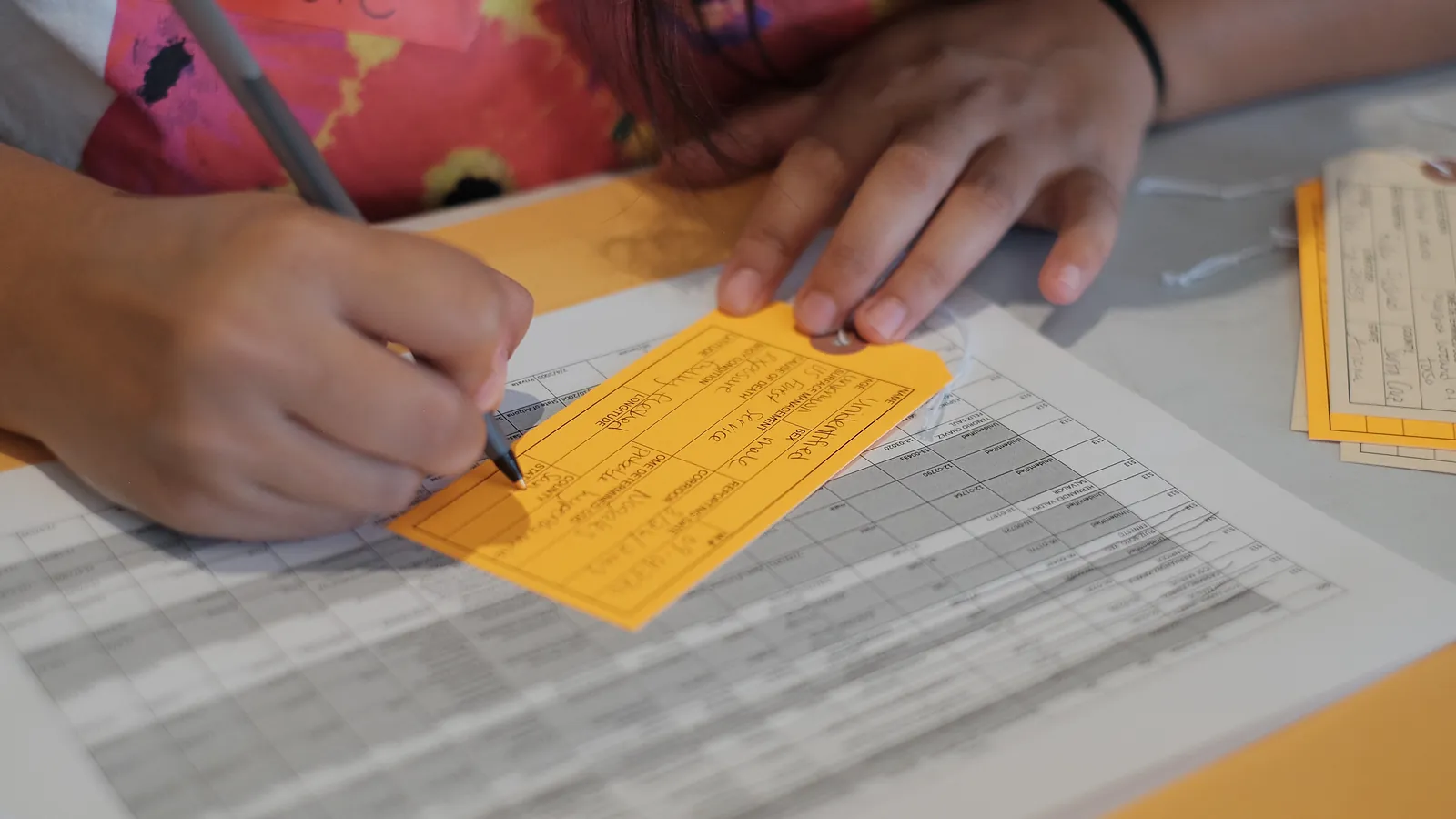 A close-up of a hand filling in a printed form with a pen on a desk