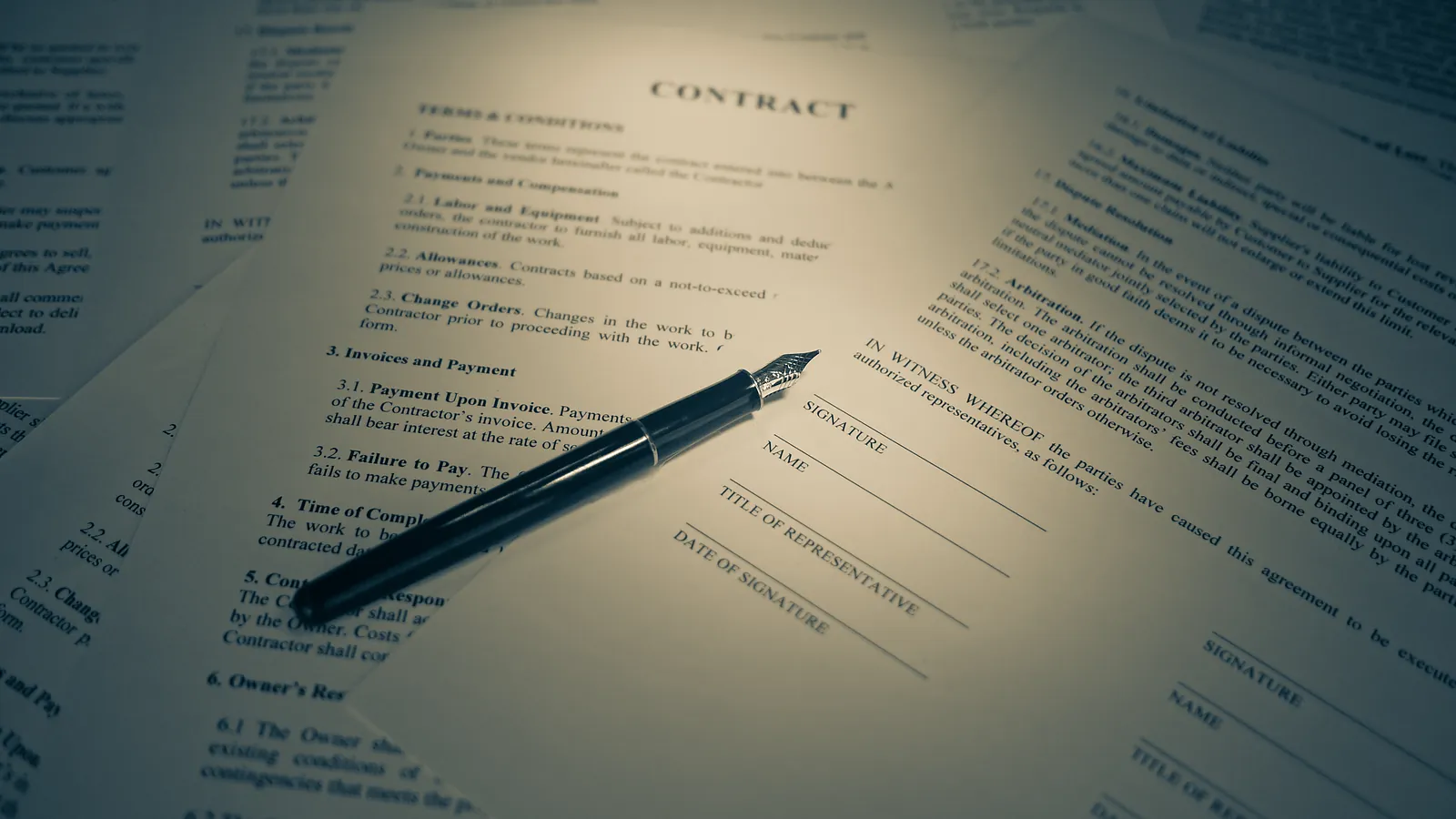 A printed contract and a fountain pen lying on a desk under soft light