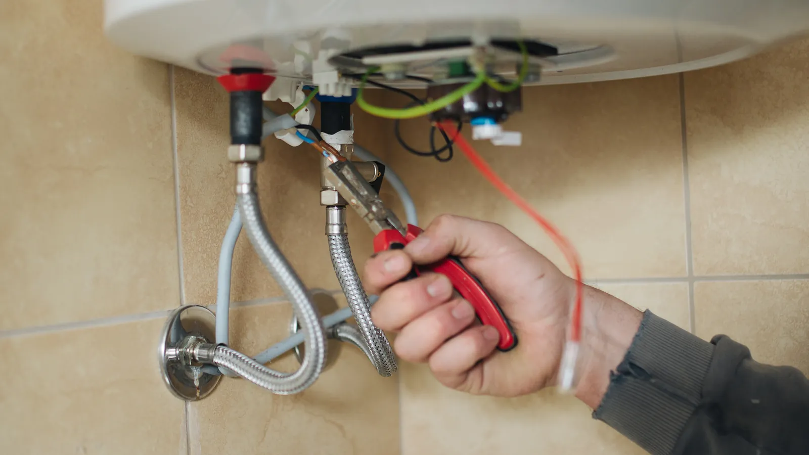 A technician working on a wall-mounted water heater in a bathroom