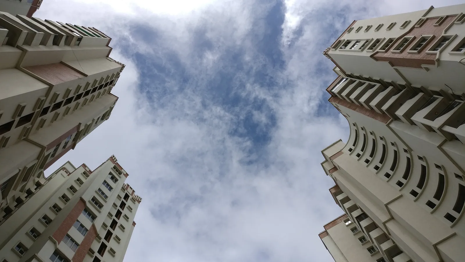 Twin residential apartment towers in Bengaluru, photographed from below against the sky