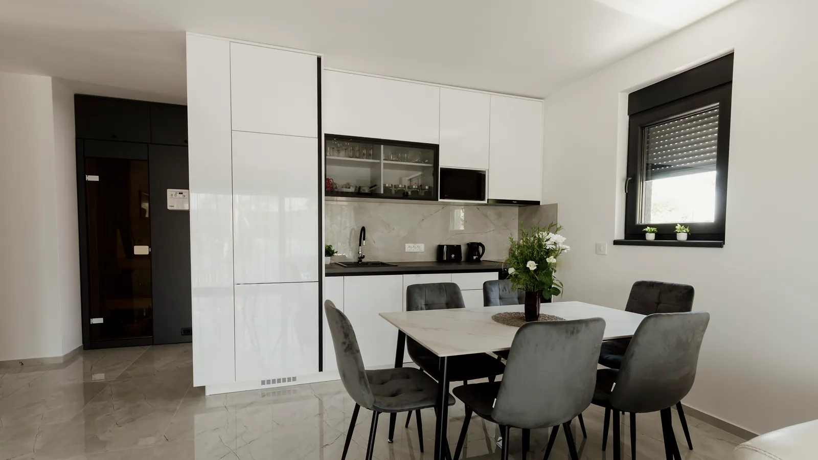A bright, furnished apartment with an open kitchen and a dining table by the window