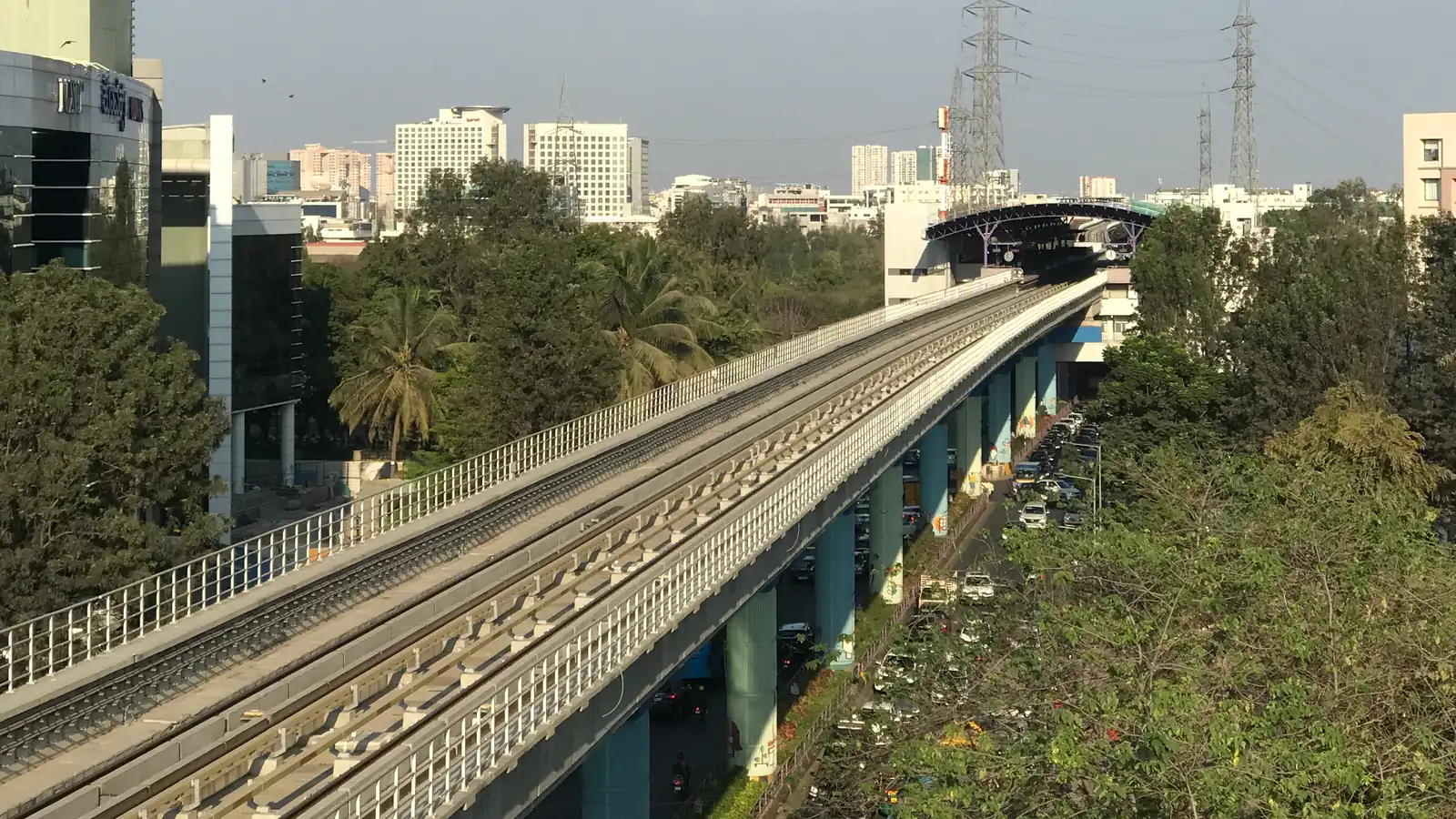 Namma Metro's Purple Line viaduct running through Brookefield towards Kundalahalli station on the Whitefield corridor, with office and apartment towers beyond the trees